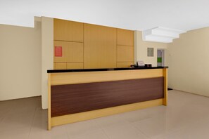 A reception desk with a wooden panel and black countertop, a red sign on the wall, and a door in the background.