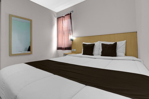 A hotel room with a bed, a nightstand, a mirror, and a window with curtains.