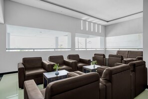 A modern hotel room with a seating area, large windows, and a view of the outside.