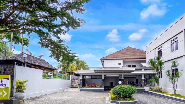 A modern hotel with a covered entrance, a stone wall, and a sign for 'DRAYA HOTEL.'