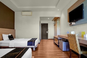 Habitación de hotel con dos camas, un escritorio, un televisor y una pequeña cocina.
