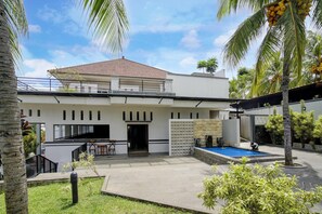 Una casa moderna de dos pisos con techo plano, un patio cubierto y una piscina.
