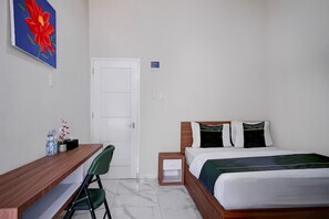 Ein Hotelzimmer mit Bett, Schreibtisch, Stuhl, einer Tür und einem Bild an der Wand.