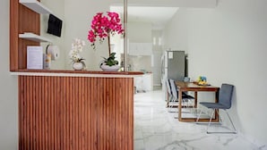 A modern kitchen with a wooden island, a dining area with a table and chairs, and a refrigerator.