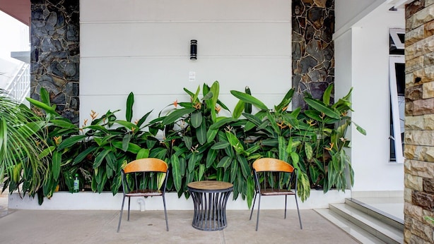 A patio area with two round tables and chairs, surrounded by lush green plants and stone walls.