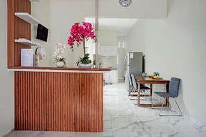 Une cuisine moderne avec un îlot central en bois, un coin repas avec une table et des chaises, et un réfrigérateur.