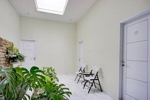 Une pièce dotée d’une lucarne, de murs blancs, d’une porte portant l’inscription « 07 », et d’un espace détente avec des chaises et une table.