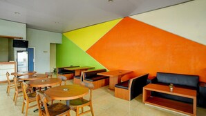 Ein modernes Interieur mit runden Tischen, Holzstühlen, einer Couch und einer farbenfrohen Wand.
