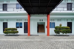A building with a covered entrance, a staircase, and two symmetrical potted plants.