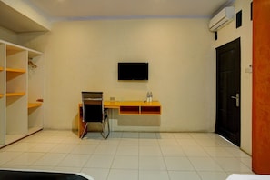 Une pièce comprenant un bureau, une chaise, un téléviseur et une armoire.