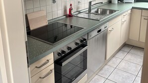 Una cucina con mobili verdi, un piano cottura nero, un lavello e un tostapane.