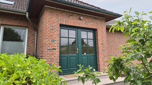 Una casa in mattoni con una porta verde, una finestra e un camino ben visibile.