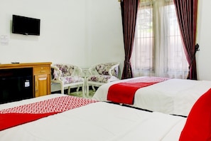 A hotel room with two beds, a desk, a chair, a TV, and a window with curtains.