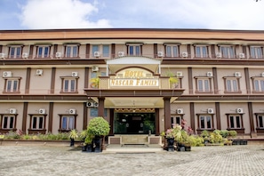 A hotel with a double-story facade, balconies, and air conditioning units.