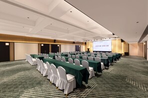 A conference room with rows of tables and chairs, a projection screen, and a carpeted floor.