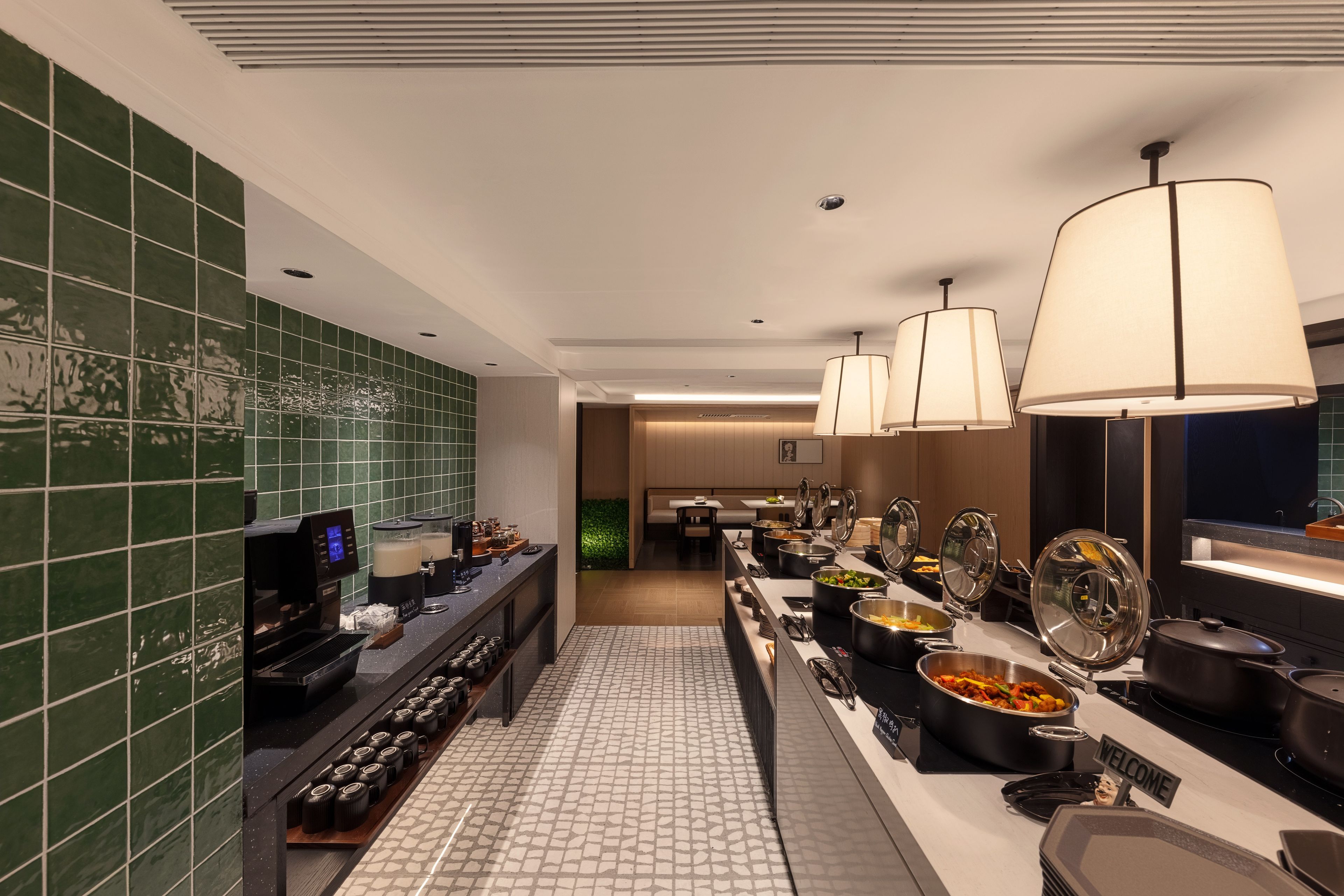Un espace dédié au petit-déjeuner à l’hôtel, avec un buffet, une machine à café et une vue sur le hall d’entrée.