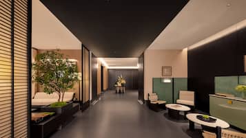 Un couloir moderne avec un canapé, une petite table, une chaise et une plante.