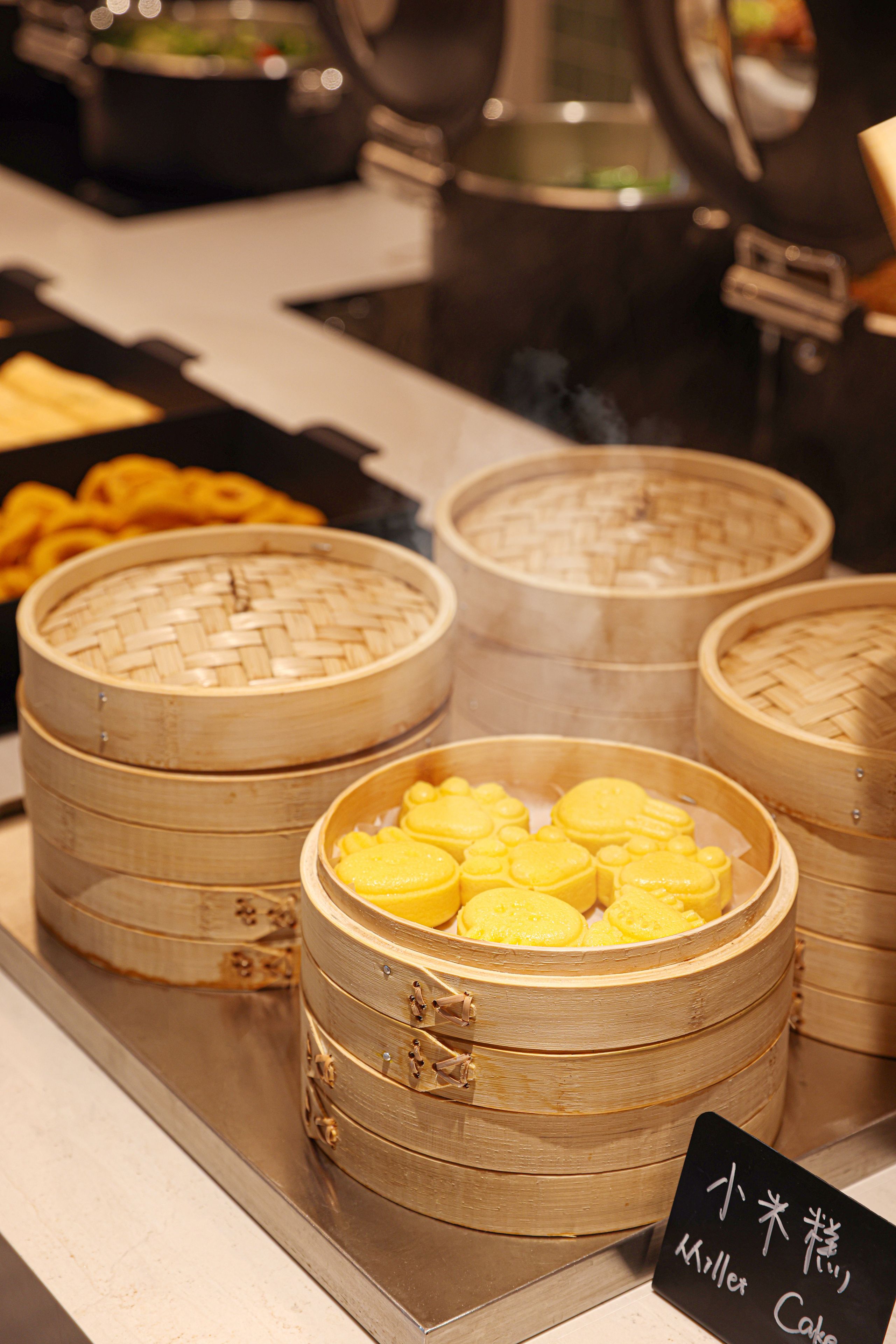 Een etalage met diverse gerechten, waaronder een mandje gele dumplings en andere lekkernijen.