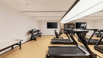 A gym with multiple treadmills, dumbbells, and exercise equipment.