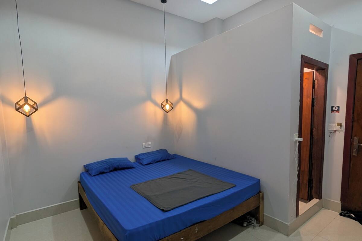 Un dormitorio con una cama, dos lámparas colgantes, una lámpara de techo y una puerta.
