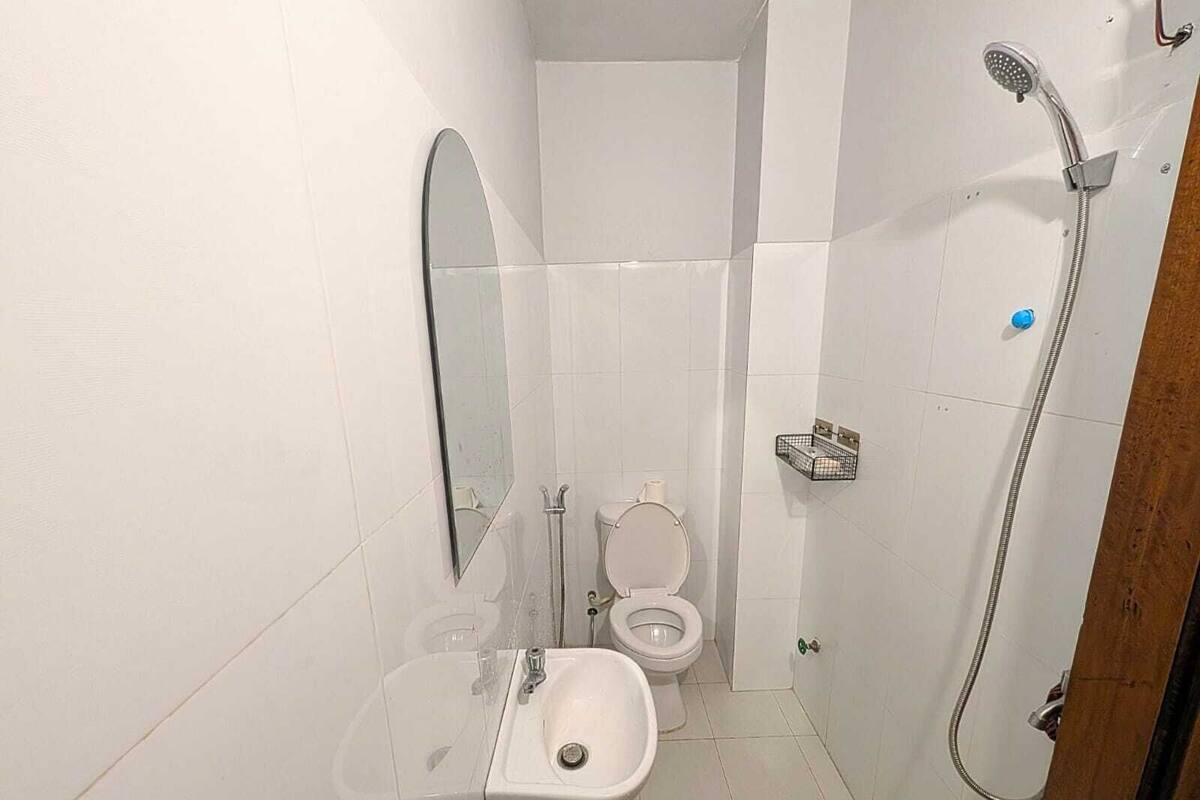 Baño pequeño y blanco con lavamanos, inodoro y ducha.