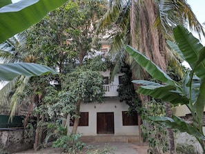 A two-story building with a balcony, surrounded by dense tropical vegetation. - Karuna Villa & Garden (Siem Reap)