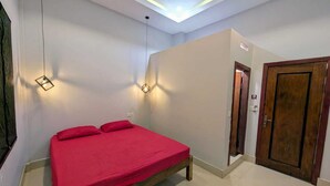 Ein Schlafzimmer mit einem Bett, zwei Wandleuchten, einer Tür und einer Deckenlampe.