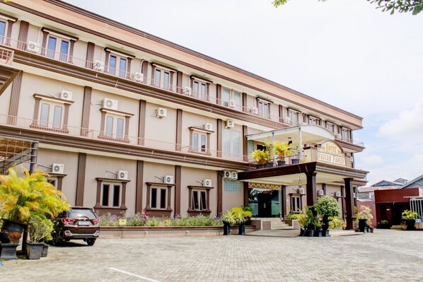 A hotel with a large entrance, multiple balconies, and air conditioning units.