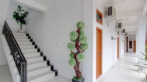 Una escalera con barandilla de metal, una planta en maceta y una escultura decorativa de árbol.
