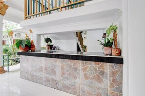 Un espace d’accueil doté d’un comptoir en pierre, de plantes en pot et d’un escalier menant à un niveau supérieur.