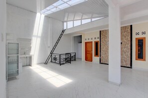 A spacious interior with a high ceiling, a staircase, and a glass partition. - Teratai Inn Cozy Double Stay (Yogyakarta)