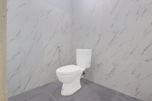 Une salle de bain avec des toilettes, des murs en marbre et des carreaux de sol gris.
