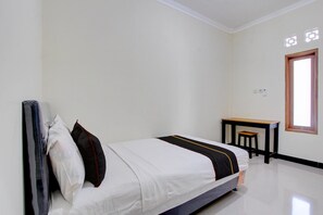 Une chambre d’hôtel propre et minimaliste, avec un lit, un petit bureau et une fenêtre.