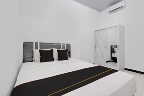 A hotel room with a bed, a wardrobe, and a mirror. - Teratai Inn Deluxe Comfort (Yogyakarta)