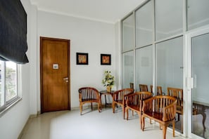 A room with a wooden door marked '101', a dining table with wooden chairs, a vase with flowers, and a large glass door.