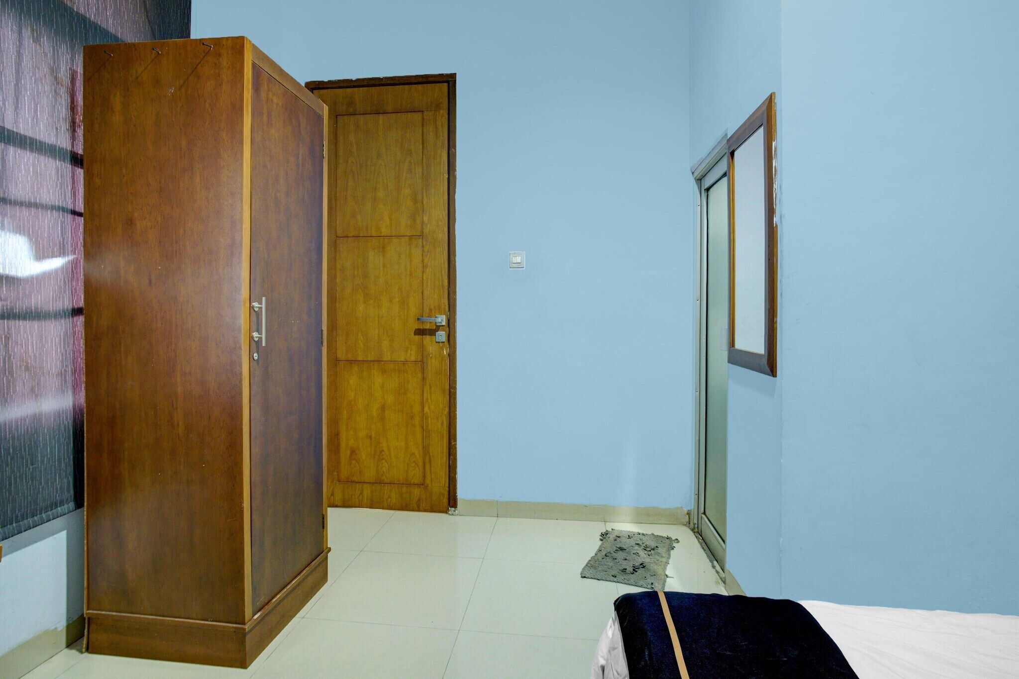 Une pièce avec une armoire en bois, une porte, un lit et une fenêtre.