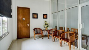 A room with a wooden door marked '101', a dining table with wooden chairs, a vase with flowers, and a large glass door.
