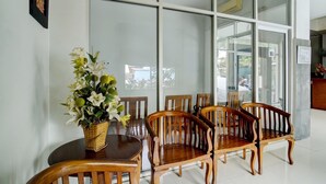 A dining area with a table and chairs, a vase of flowers, and a large window with reflections.