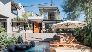 A modern pool area with a floating ring, lounge chairs, and an umbrella.