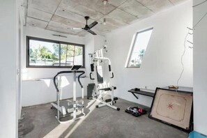 A gym with exercise equipment, a ceiling fan, and a window.