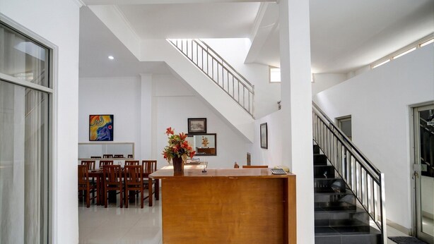 A spacious interior with a reception desk, dining area, staircase, and artwork on the walls.