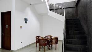 A staircase with a metal railing, a wooden door, and a table with chairs in a hallway.
