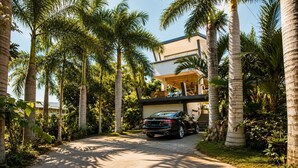 A modern house with a car parked in the driveway, surrounded by palm trees. - Private tropical loft in shared villa + pool + jacuzzi (Port Louis)
