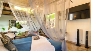 A bedroom with a bed, canopy, bedside table, lamp, and a TV mounted on the wall. - Private tropical loft in shared villa + pool + jacuzzi (Port Louis)