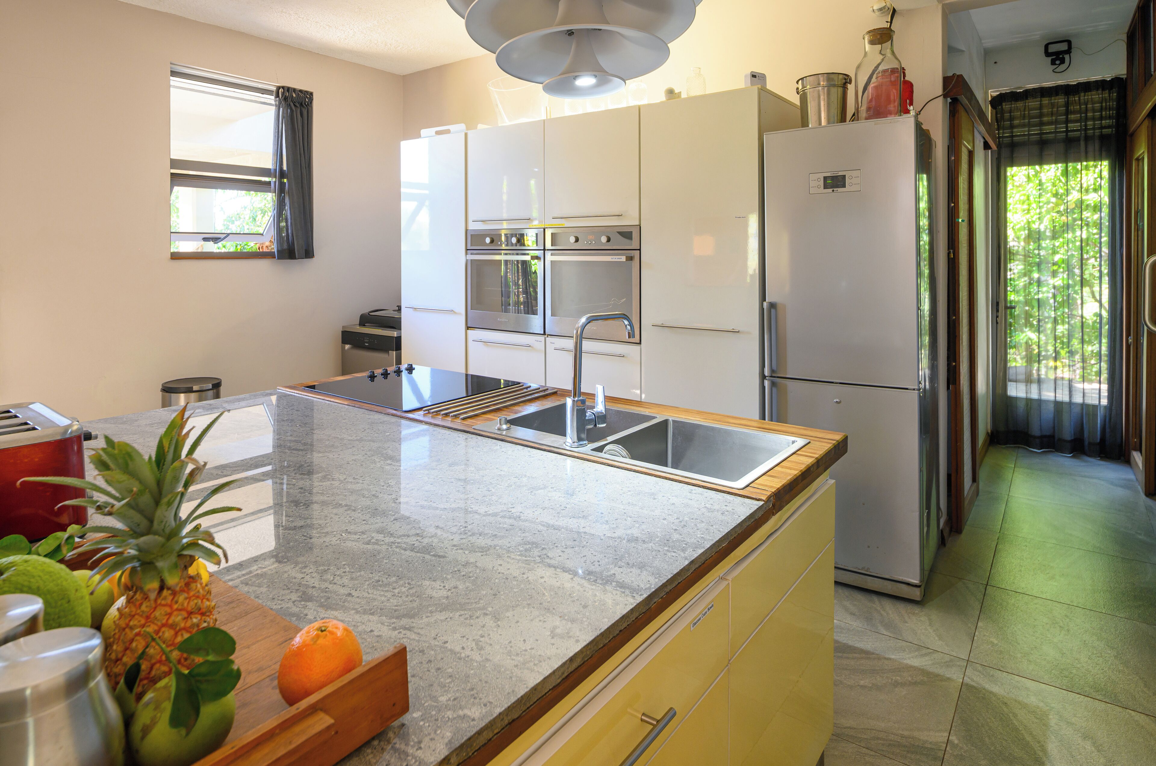 Eine Küche mit Granit Arbeitsplatte, Edelstahlgeräten und einem Fenster mit Vorhängen.