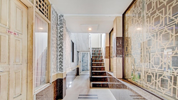Un pasillo de hotel con una escalera, suelo de mármol y paredes con diseño.