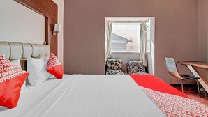 Una habitación de hotel con una cama, un escritorio y una ventana.