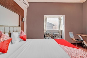 A hotel room with a bed, a desk, and a window.