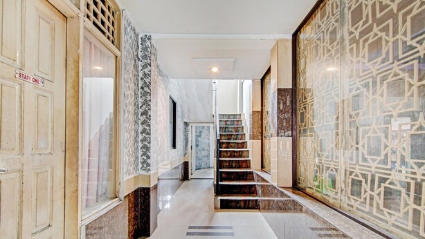 Un pasillo de hotel con una escalera, suelo de mármol y paredes con diseño.