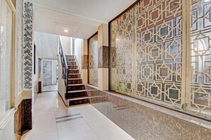 A hallway with a marble floor, a staircase with a patterned wall, and a geometric wall design.